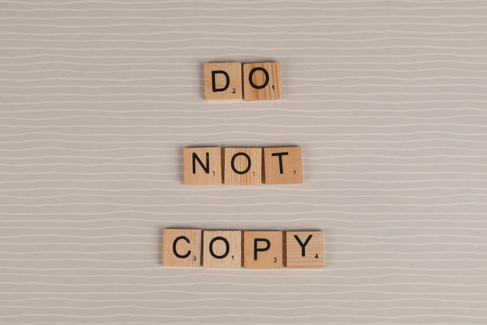 ตัวอักษรไม้เรียงเป็นคำว่า DO NOT COPY บนพื้นสีเทาอ่อน
