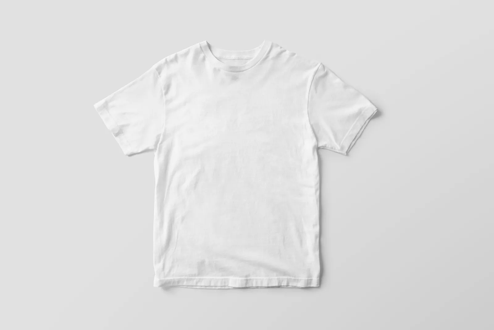 เสื้อยืดสีขาววางราบบนพื้นสีเทาอ่อนสีเดียว ถ่ายจากด้านบน