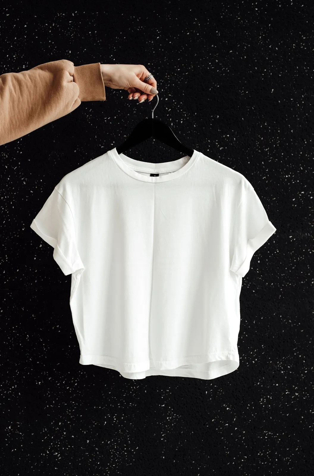 เสื้อยืดสีขาวแขวนอยู่บนผนังสีดำ